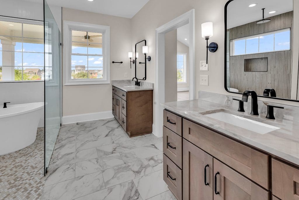 Bright, modern bathroom in a custom Myrtle Beach home featuring dual vanities, marble tile, and natural light.
