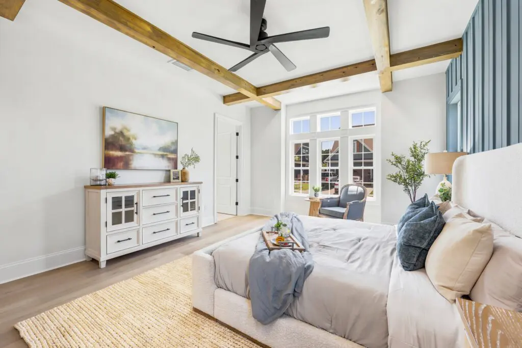 Bright custom home living room with exposed wood beams, large windows, and open-concept design, showcasing features to consider when choosing a lot for a custom home.