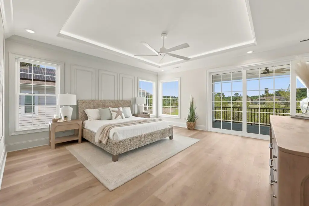 Luxury primary bedroom in a custom home built by a Myrtle Beach custom home builder featuring tray ceilings, expansive windows, and a private outdoor living space.