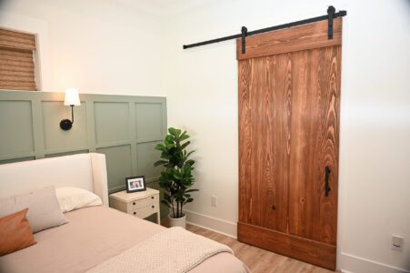 A cozy coastal private suite with a sage green accent wall, a sliding barn door, and warm, inviting decor.