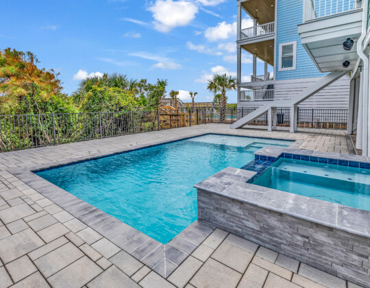 Private backyard pool and spa at a coastal custom home in Myrtle Beach, featuring durable hardscaping, outdoor living space, and elevated construction—highlighting lifestyle upgrades that can impact the overall cost of building a custom home.