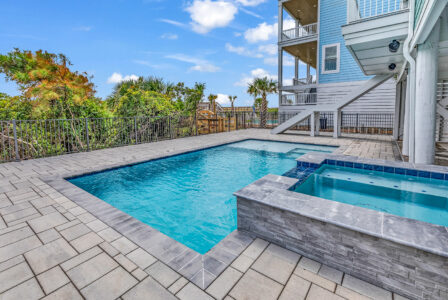 Private backyard pool and spa at a coastal custom home in Myrtle Beach, featuring durable hardscaping, outdoor living space, and elevated construction—highlighting lifestyle upgrades that can impact the overall cost of building a custom home.