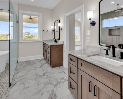 Bright, modern bathroom in a custom Myrtle Beach home featuring dual vanities, marble tile, and natural light.